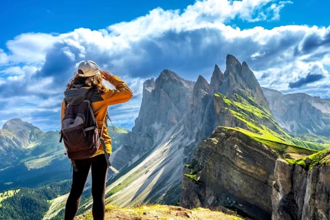Hiker shielding her eyes while enjoying the breathtaking view of the odle mountain range in the