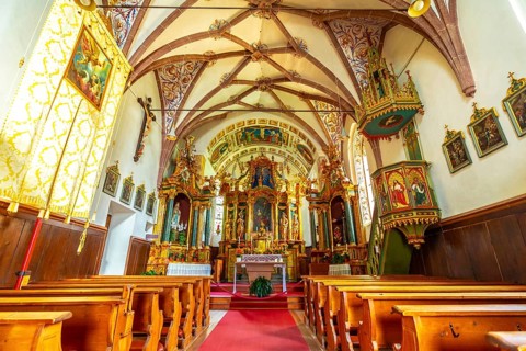 Featuring a richly decorated altar, vibrant frescoes, and a traditional wooden pulpit, the interior