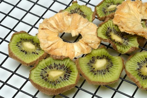 Dried pineapple slices and dried kiwi slices on a wire rack