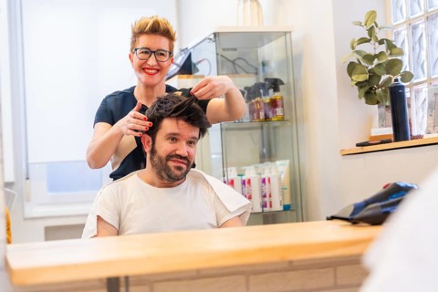 Reflection on the mirror of a cool hairdresser and man with new capillary prosthesis in the salon