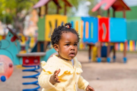 A little african girl playing on playground under the sun