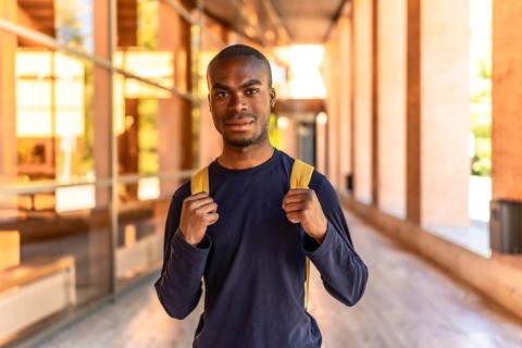 Frontal portrait of a young African student standing looking at camera at the university