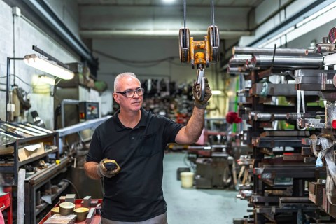 Mature caucasian man using remote control to operating a crane in a metal factory