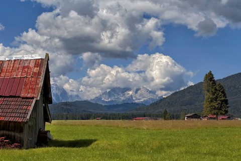 A peaceful alpine landscape with meadows, an old barn and mountains in the background, Wallgau,