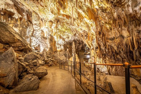 Tourists visiting the famous postojna cave, located in slovenia, walking on illuminated cemented