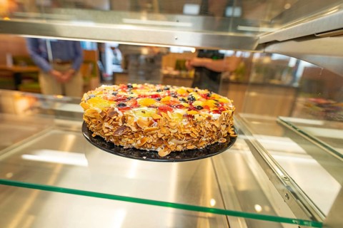 An artistically decorated cake with almond slivers and fruit in a glass display case, Cafe Kuh,