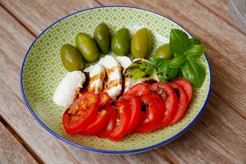 Mediterranean cuisine, cocktail tomatoes, green olives, buffalo mozzarella arranged on a plate,