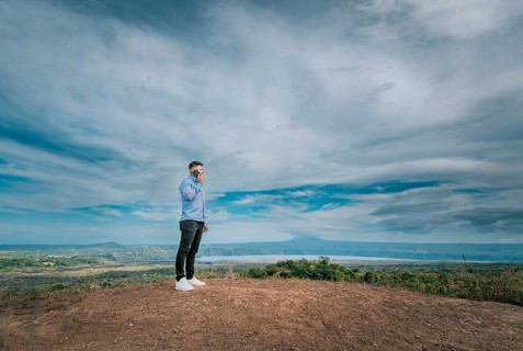 Young man talking on the phone at a viewpoint surrounded by nature. Man talking on the phone at a