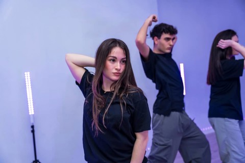 Group of young dancers practicing a modern choreography in a dance studio illuminated by purple
