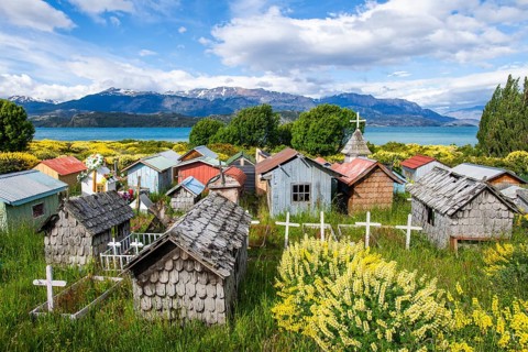 Colourful plastic flowers and graves with miniature houses made of corrugated iron and wooden