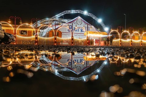 Nocturnal circus reflected in a pool of water, with illuminated arches and lights, Böblingen,