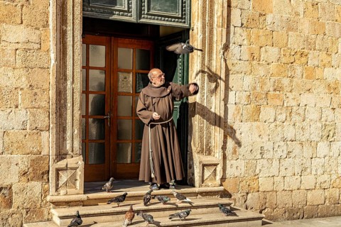 Monk feeding the pigeons in front of the Franciscan monastery in Dubrovnik, Croatia, Europe