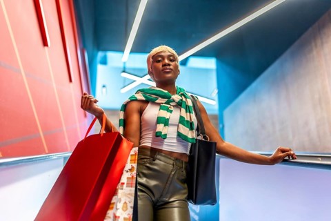Low angle view portrait of a stylish african woman with short hair coming down an escalator
