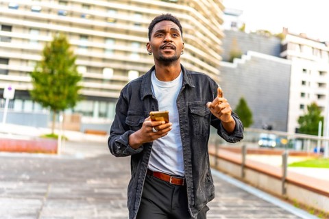 African man walking along the city using gps app to find a direction