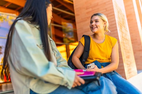 Female chinese and caucasian exchange university students talking outside the university building