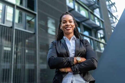 Migrant latin confident woman standing with arms crossed smiling at camera in a financial district