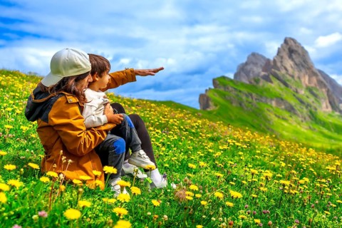 Mother and child admiring the landscape in the seceda mountains in the dolomites, italy, during a