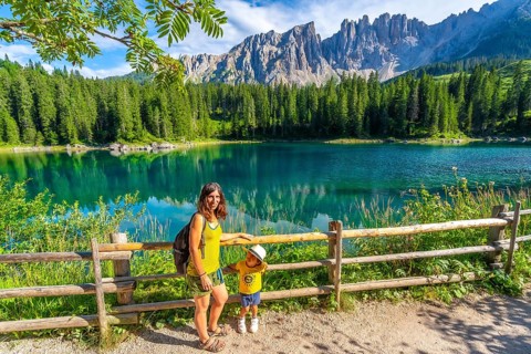 Mother and child enjoying summer holidays at the magnificent lake carezza with the latemar massif
