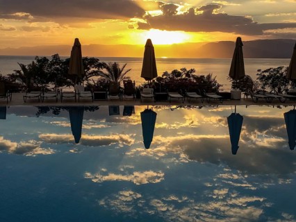 Sunset illuminated Red Sea and clouds Altostratus closed parasols reflected in swimming pool,