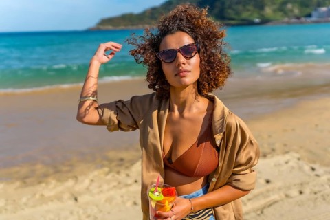 Sensual arab woman walking along topical beach with a glass of fruit