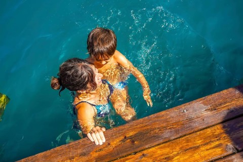 Mother and son having fun swimming in the turquoise water of lake bled, a popular tourist