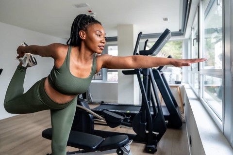 Manager stretching legs in hotel fitness room during business trip, maintaining healthy lifestyle