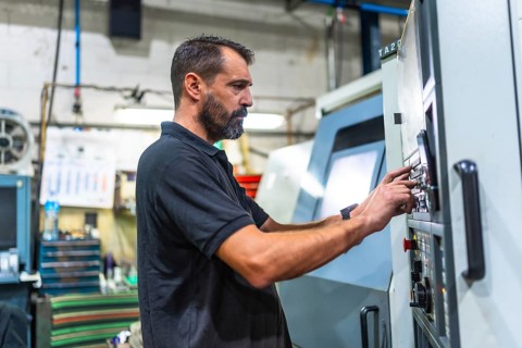 Side view of a mature caucasian man working in the control station of a cnc factory