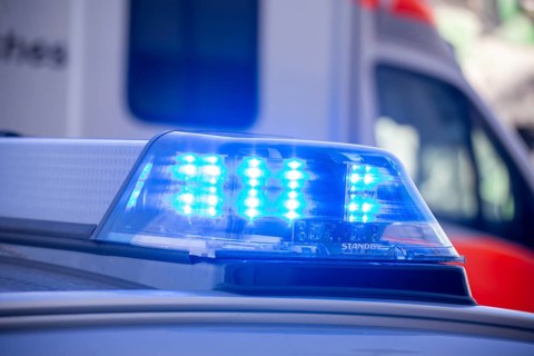 Close-up of flashing blue lights during a police operation with an ambulance in the background