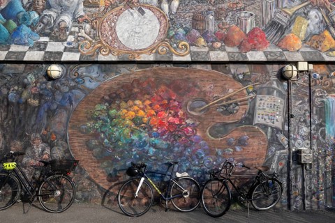 Bicycles in front of a house wall with large-format graffiti of a colour palette, Sølvgades Skole,