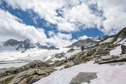 Mountaineer on a hiking trail between snow, descent from the summit of Schönbichler Horn, view of