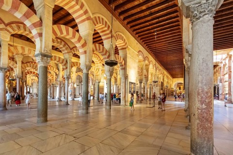 Large interior with numerous columns and arches, populated by people, Cordoba