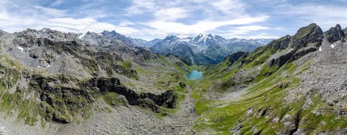 Alpine panorama, aerial view, mountain stream and mountain lake Lac de Louvie with glaciated summit