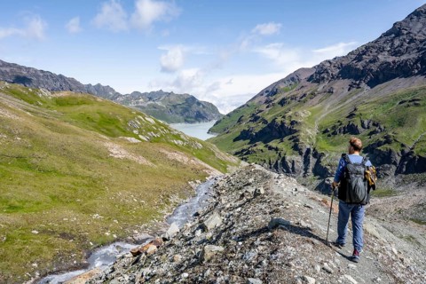 Mountaineers on a hiking trail by a mountain stream, behind the Lac des Dix reservoir, Valais Alps,