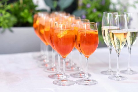Glasses with orange colored Spritz, a wine-based cocktail drink on table in restaurant at wedding