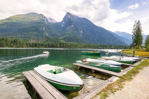 Jetty with boats at Hintersee, with green mountains in the background, peaceful and idyllic natural