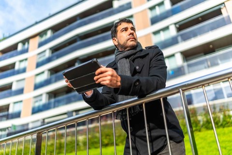 Low angle view portrait of a casual adult caucasian businessman using digital tablet leaning on