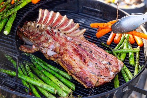 Barbecue with Easter roast. Rack of lamb and green asparagus grilled on an outdoor kettle barbecue.