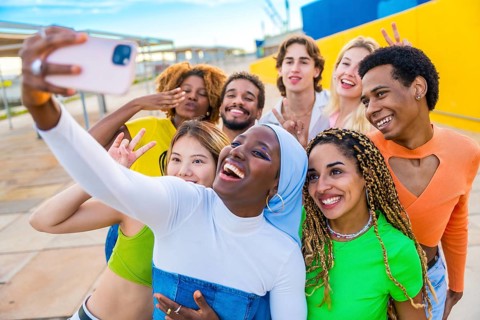 Cheerful muslim african woman taking a selfie with friends in an urban space