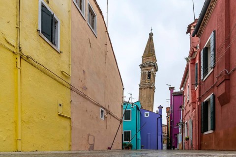 City view of Burano with colourfully painted houses and canals. Slate church tower Campanile,