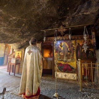 A clergyman stands in front of a scenic decorated room in a church during a service, rock grotto,