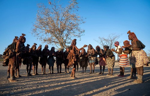Group of traditional Himba woman standing in a semi-circle, clapping and dancing, music and dance,