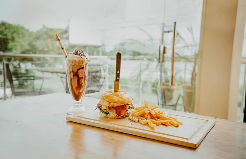 Close up of burger with fries and milkshake on wooden board with space for text. Delicious big