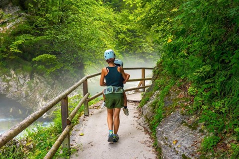 Mother carrying her child while hiking on a misty summer day in vintgar gorge near bled, slovenia,