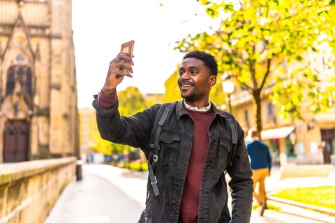 African man taking photos of a city while walking and visiting it during sunset