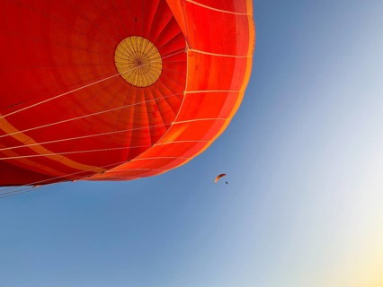 Hot air balloon ride, Paraglider with motor passes the hot air balloon. Background blue sky. Alice