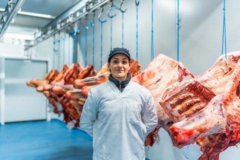 Caucasian adult female manual worker standing proud in a meat processing factory