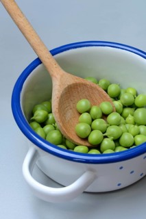 Fresh green peas in pot with wooden spoon, Pisum sativum