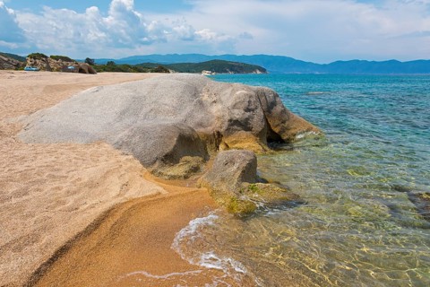 Rocky beach with clear sea water and gentle waves, surrounded by nature, beach, rocks in the shape