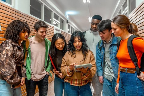 Diverse group of college students collaborating on a project, using a digital tablet in a
