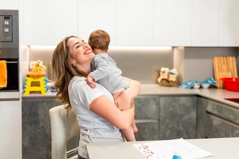 Mom lovingly embraces her baby in a modern kitchen, creating a heartwarming moment of family